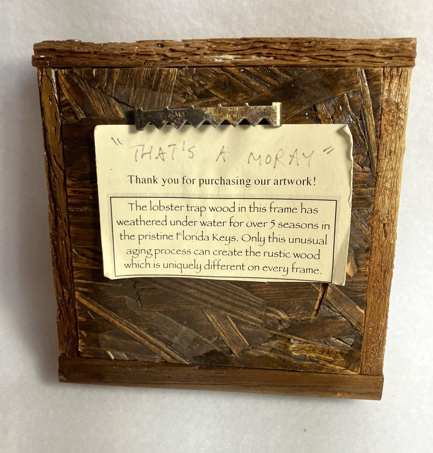 Distressed wooden frame with a rustic finish and a message card about the origin of the frame