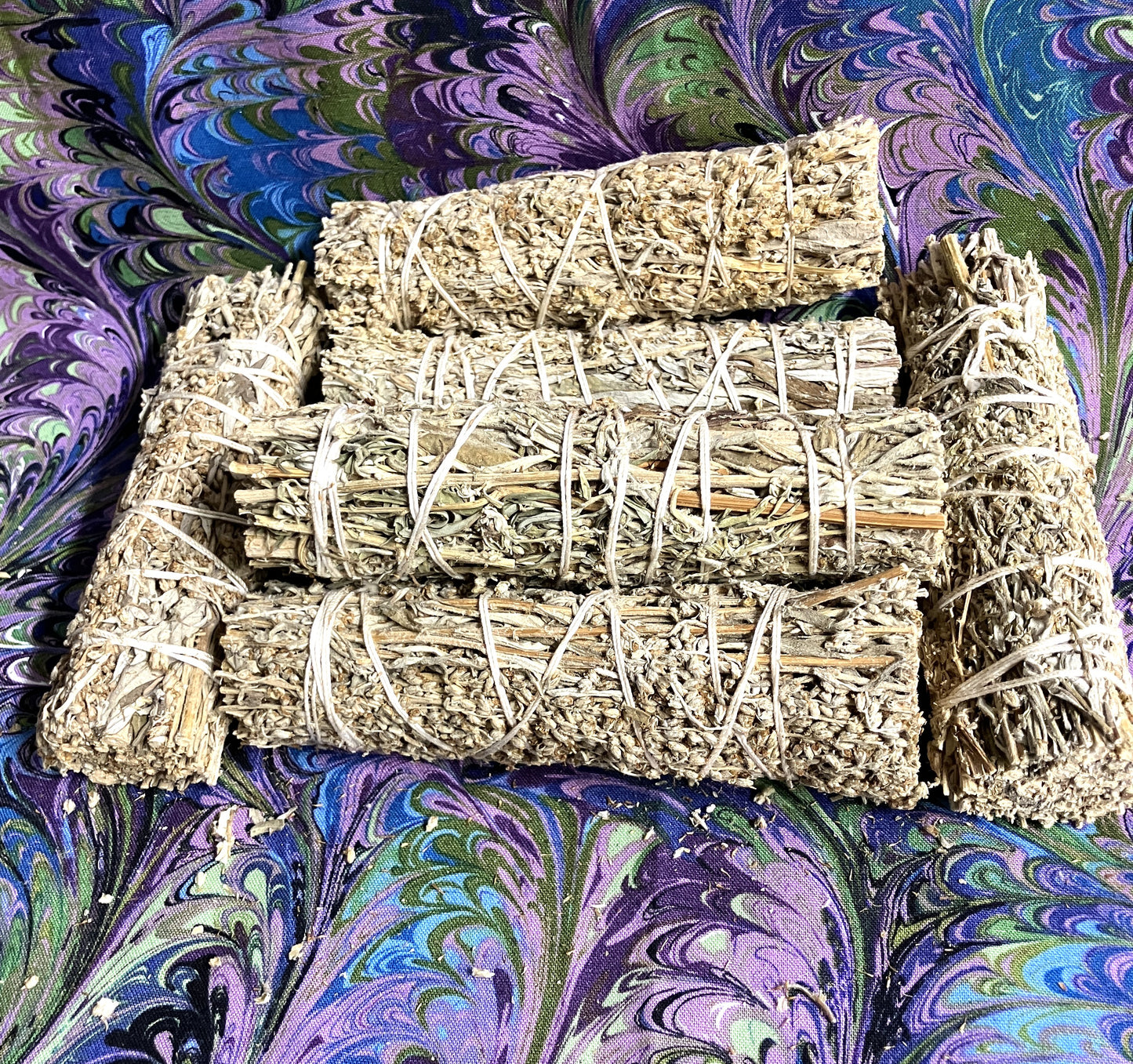 Several bundles of Mugwort on a colorful, patterned fabric background