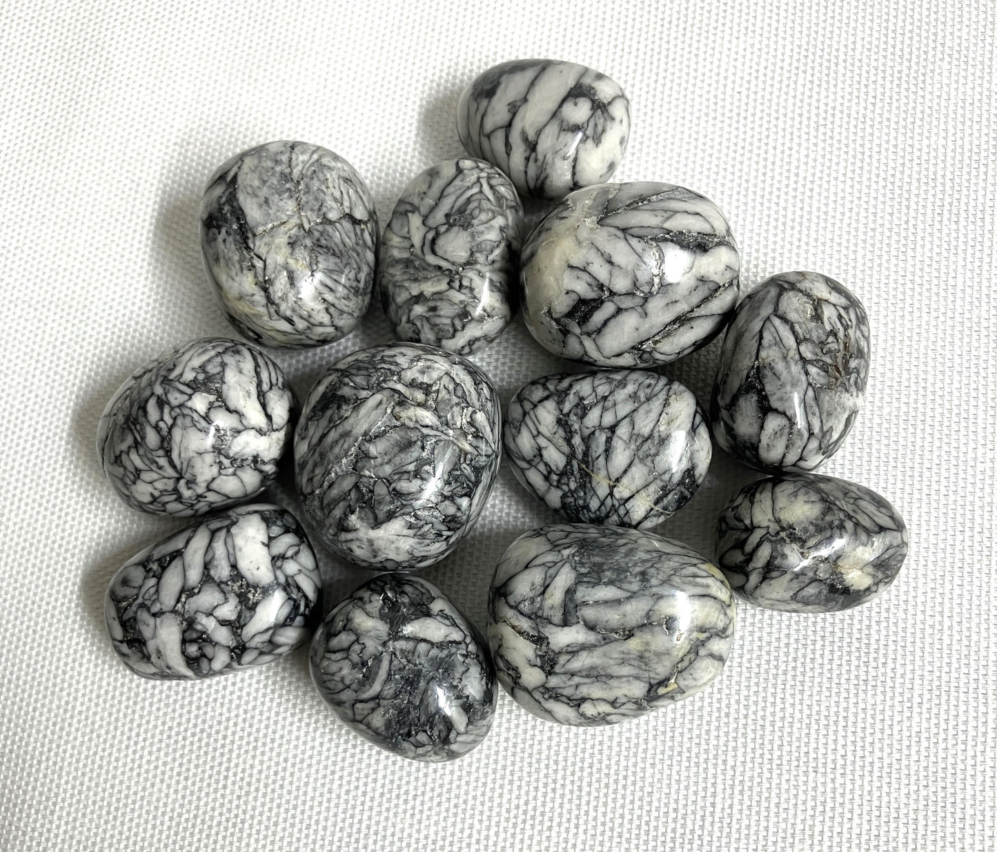 Tumbled Pinolith Jasper Crystals shown on a textured surface