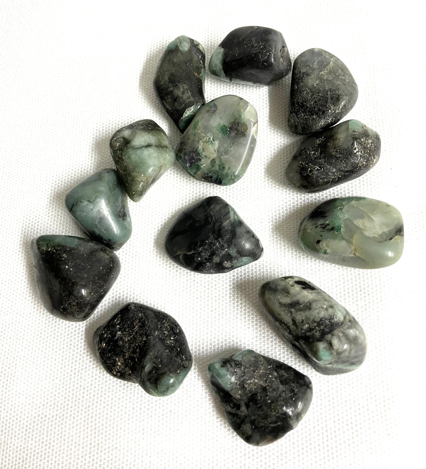 Collection of Emerald Crystals showing the formation of the stones on a white fabric background