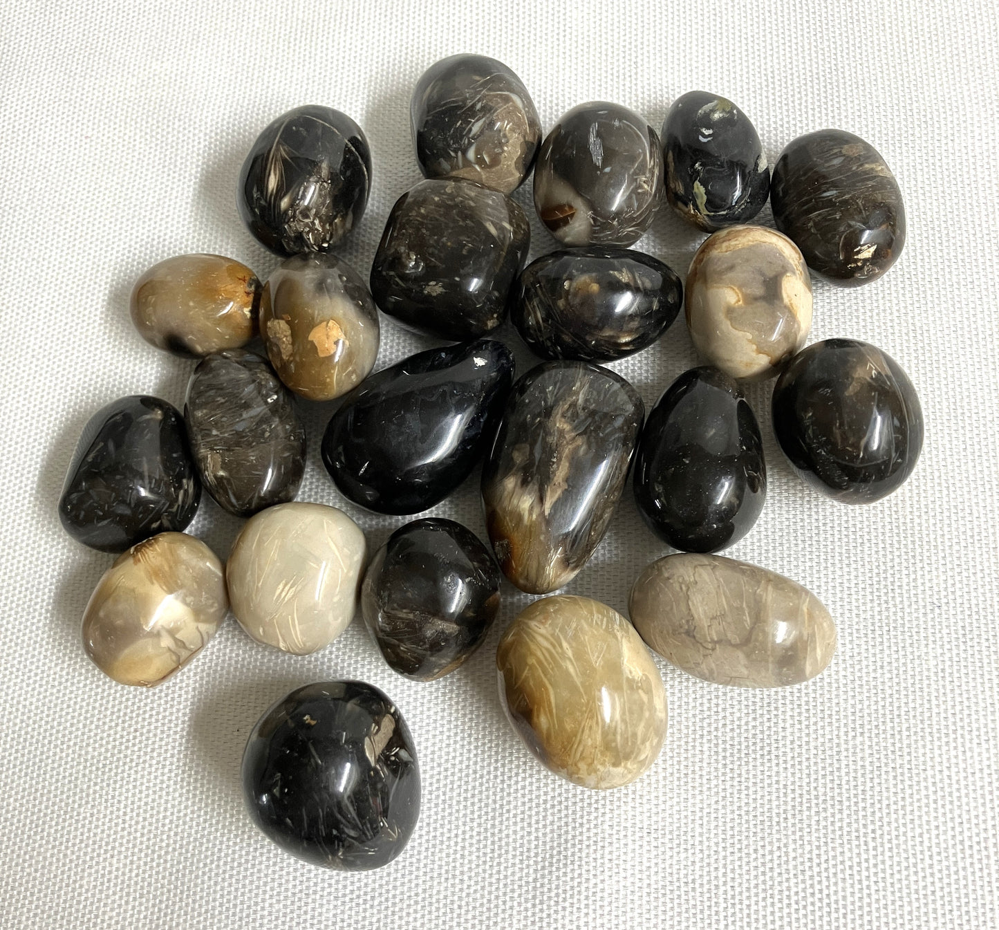 Feather Agate Tumbled Crystals showing the variations of pattern on a white fabric background