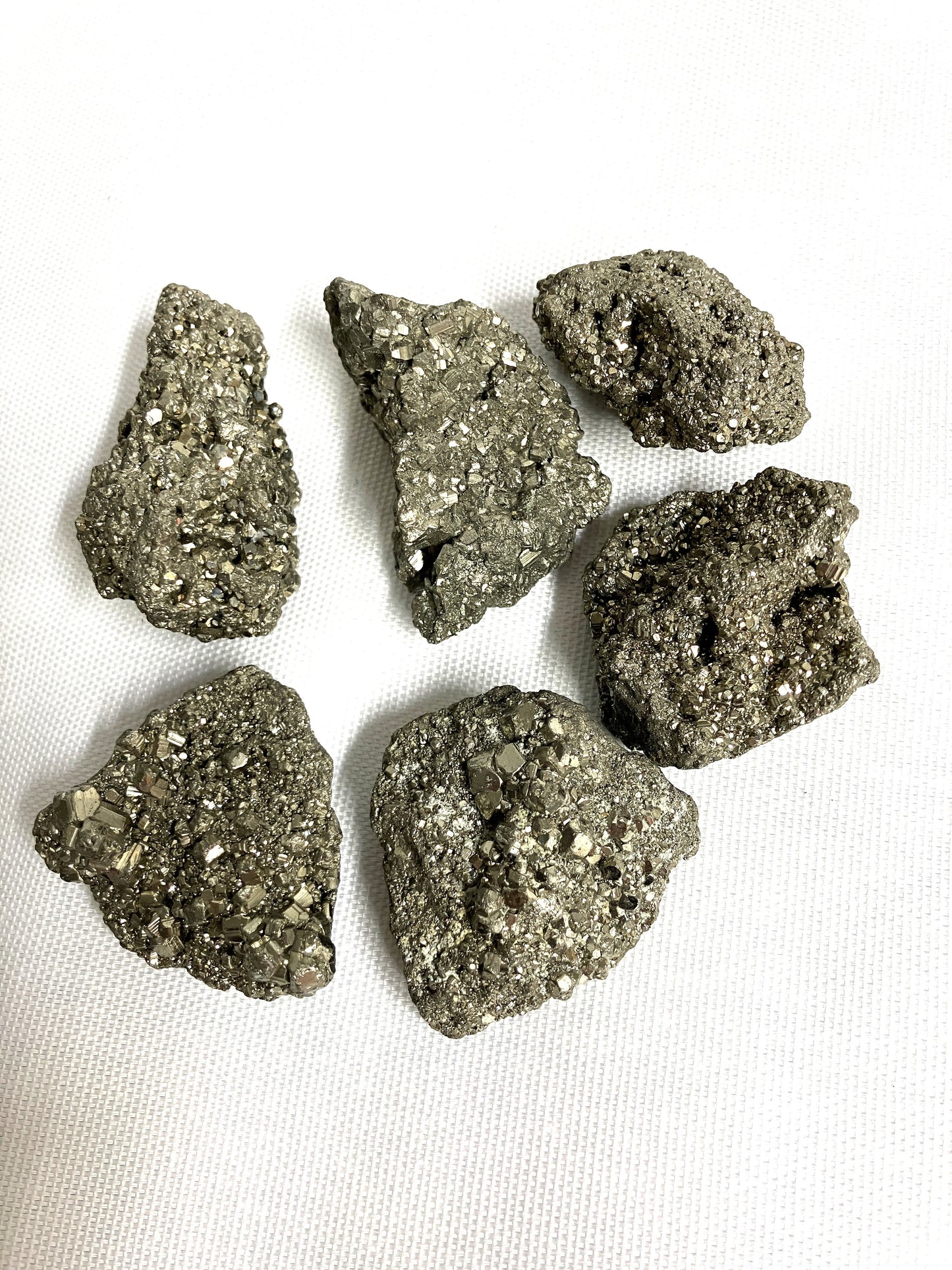 Closeup of Natural Pyrite Crystals AKA Fools Gold on a white fabric background