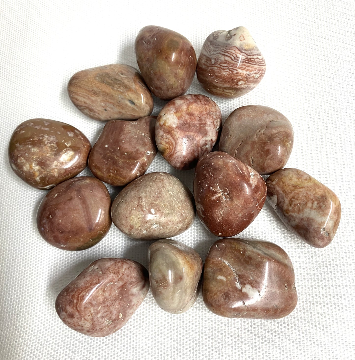 Collection of Crazy Lace Agate Crystals showing variations on a white fabric background