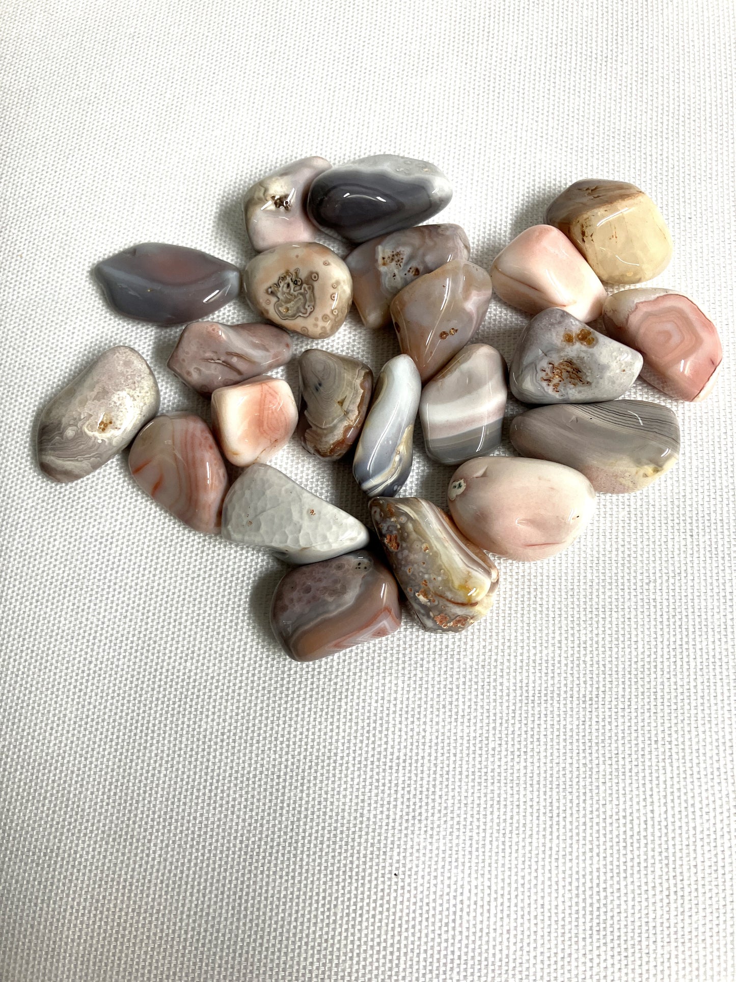 Group of Tumbled Botswana Agate Crystals on a textured white surface