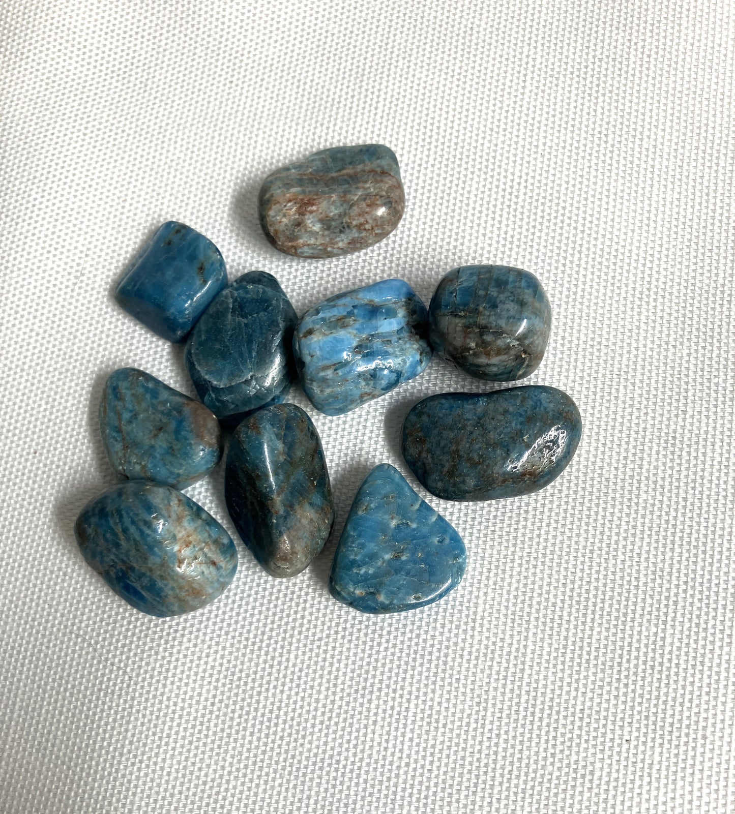 Group of Blue Apatite Crystals showing the pattern and colors on a textured white surface