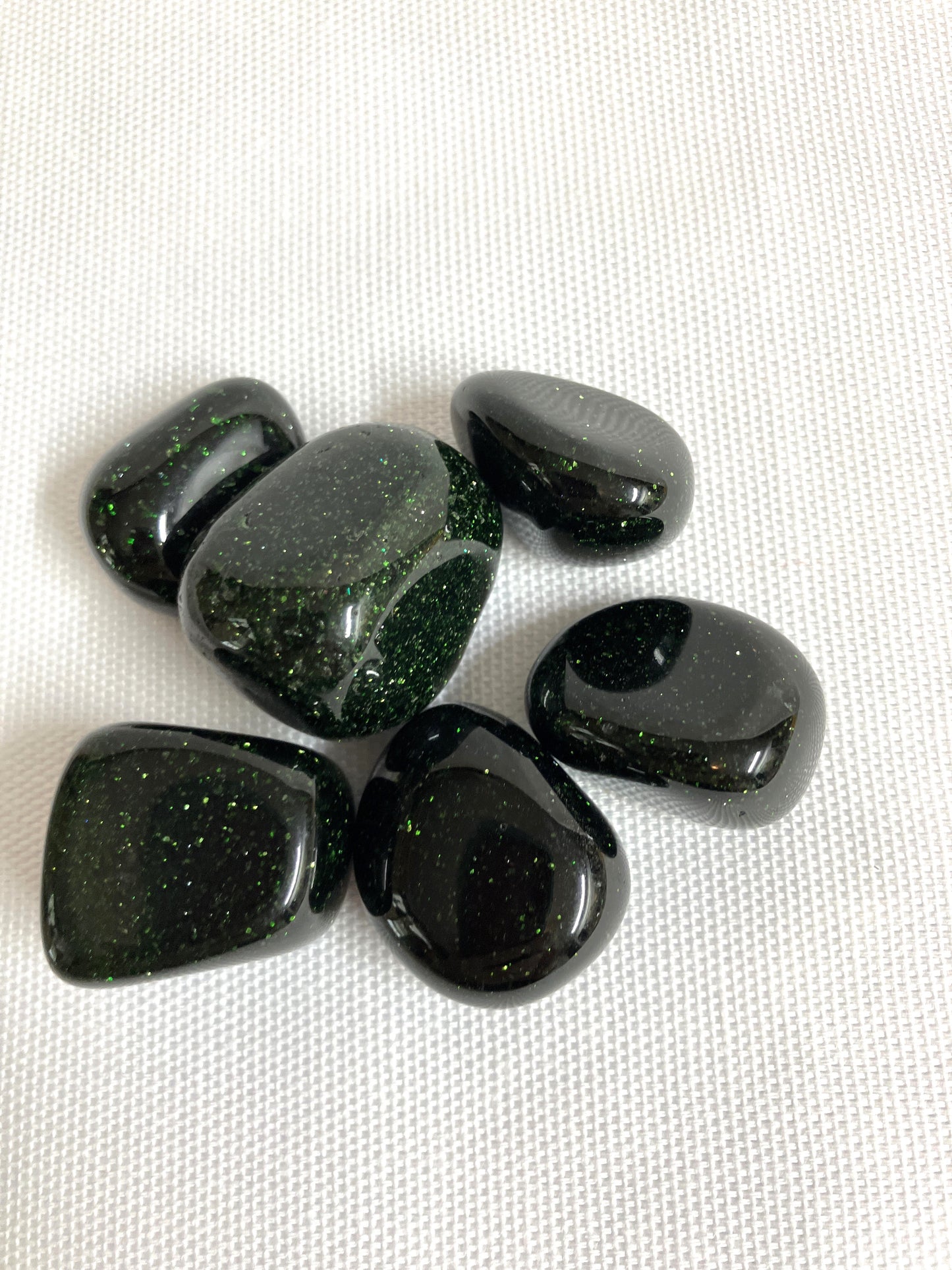 Closeup of Tumbled Green Goldstone Crystals on a white background
