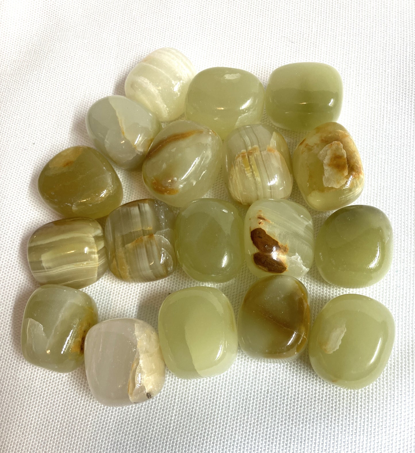 Tumbled Green Calcite Crystals on a white fabric background