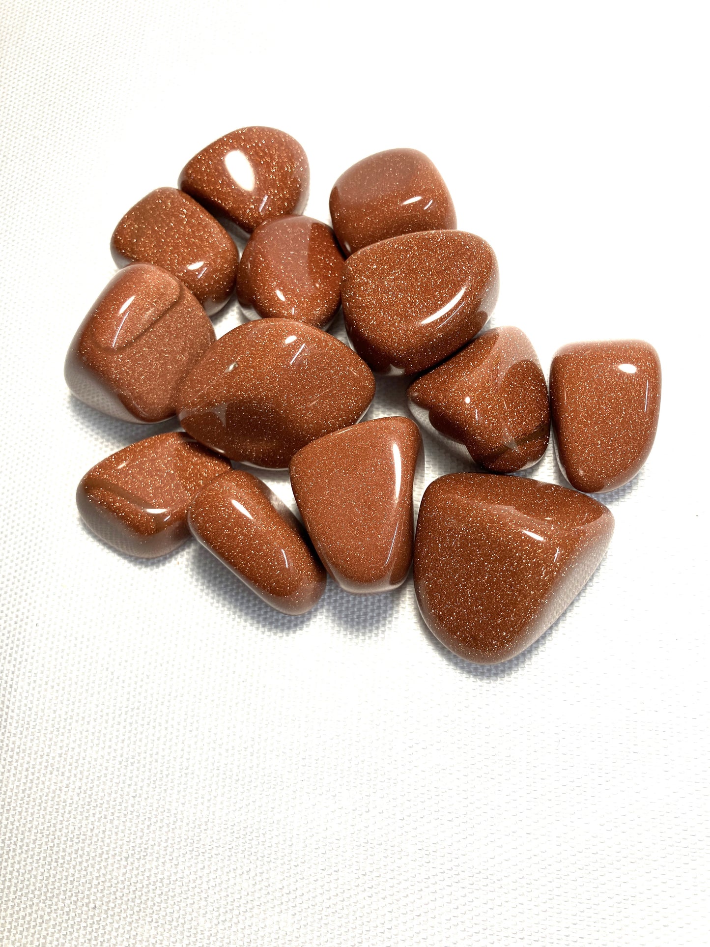 Red Goldstone Crystals with views of the variations in each piece on a white background