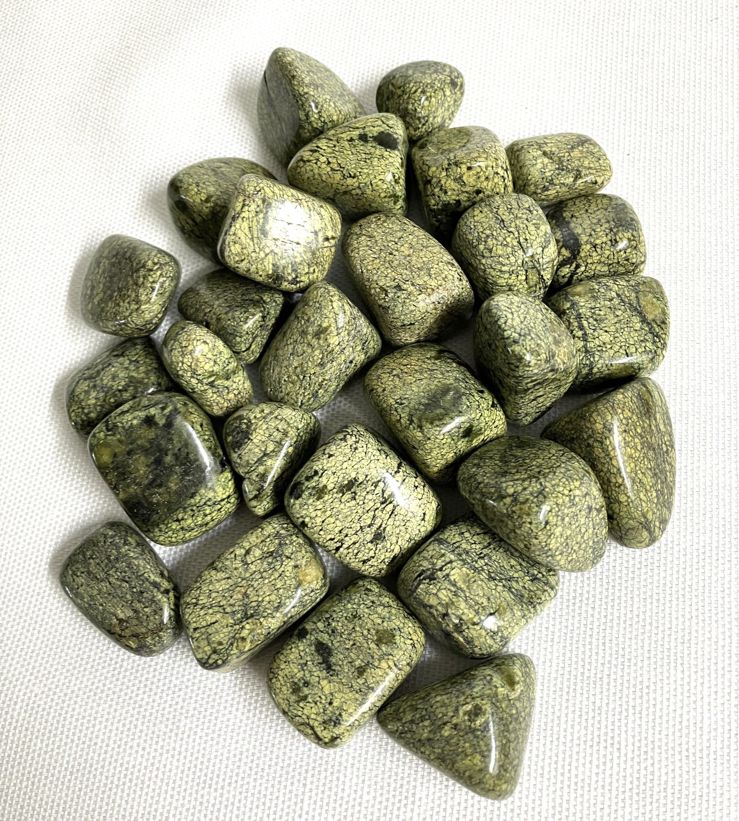 Tumbled Asterite Serpentine Crystals on a white fabric background