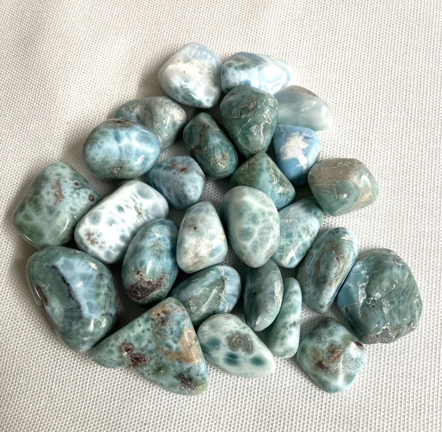 Collection of Larimar Crystals showing the pattern on a light fabric background