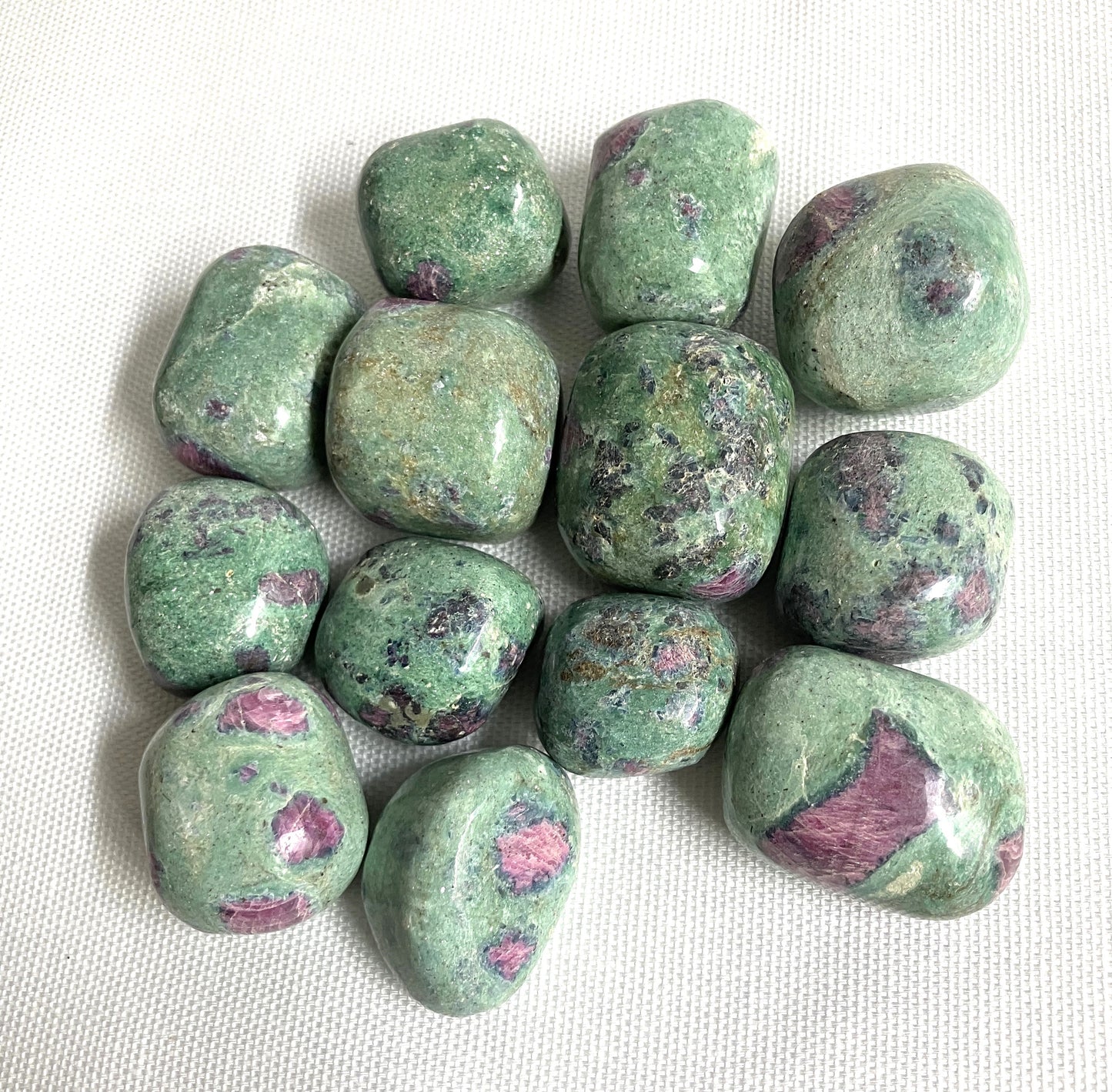 Closeup of a group of Ruby Fuchsite Crystals on a white fabric background