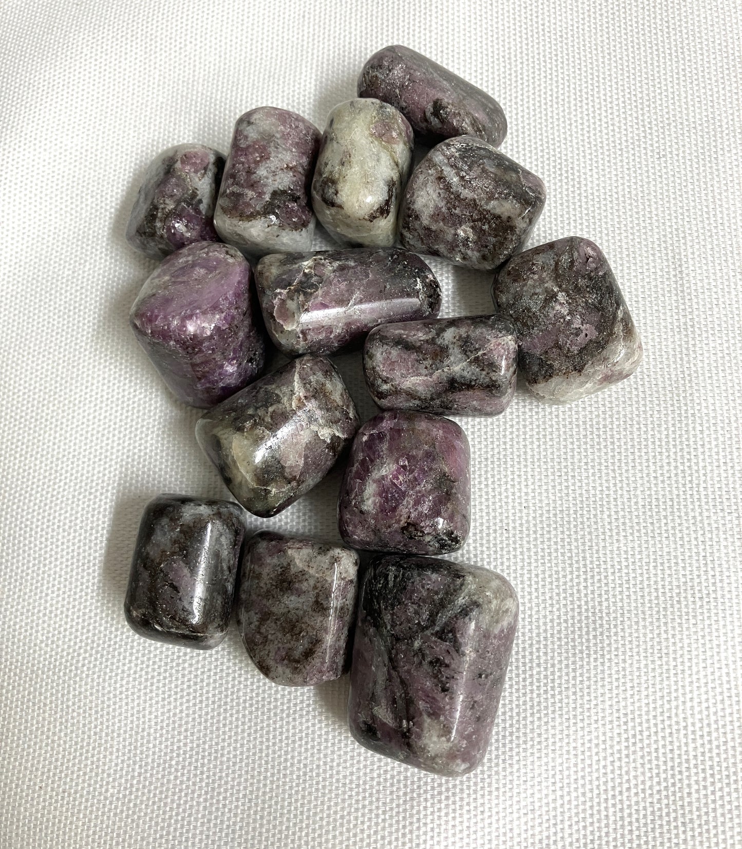 Bottom side of Pink Garnet Tumbled Crystals on a white fabric background