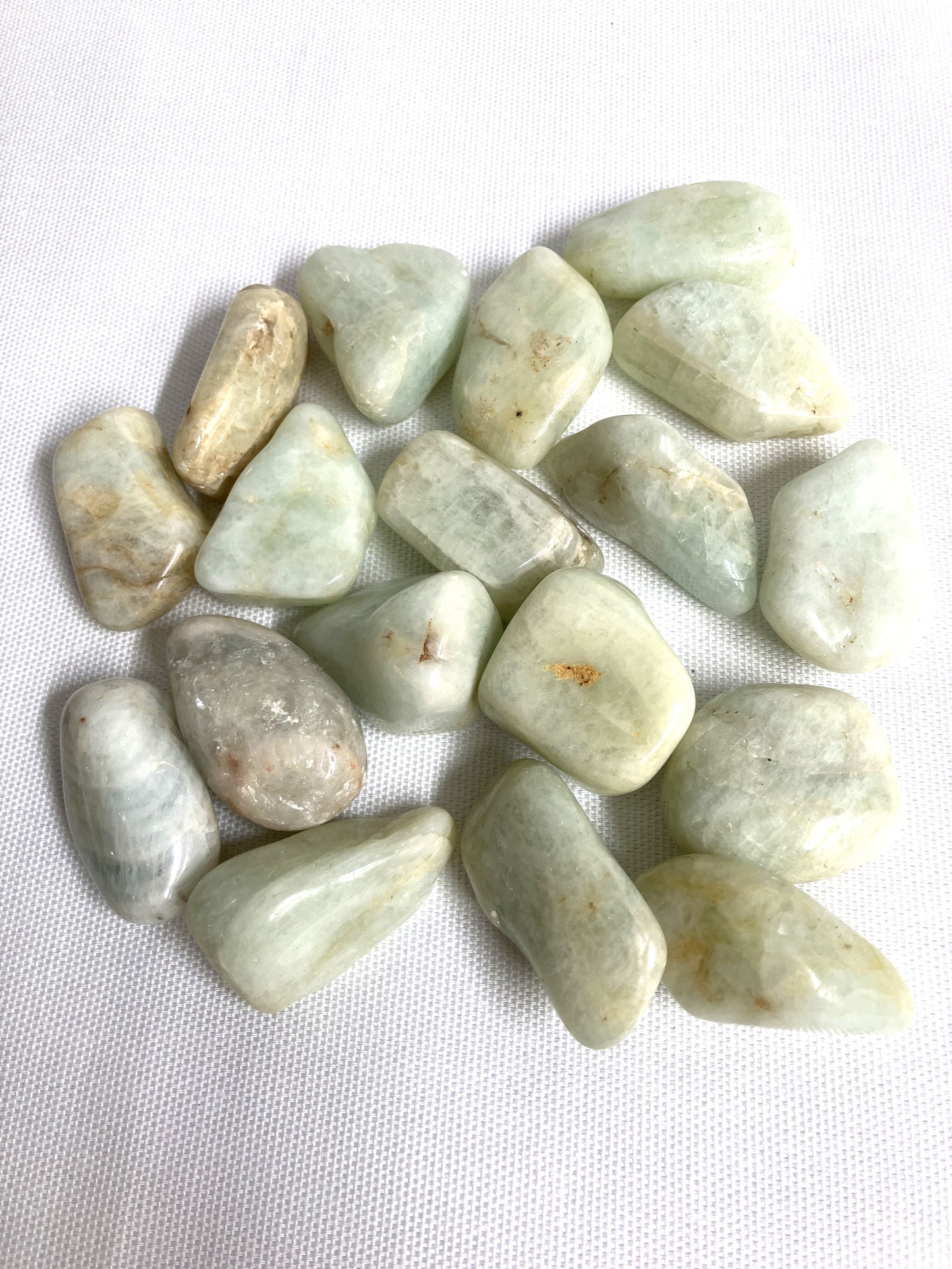 Tumbled Aquamarine Crystals on a white fabric background
