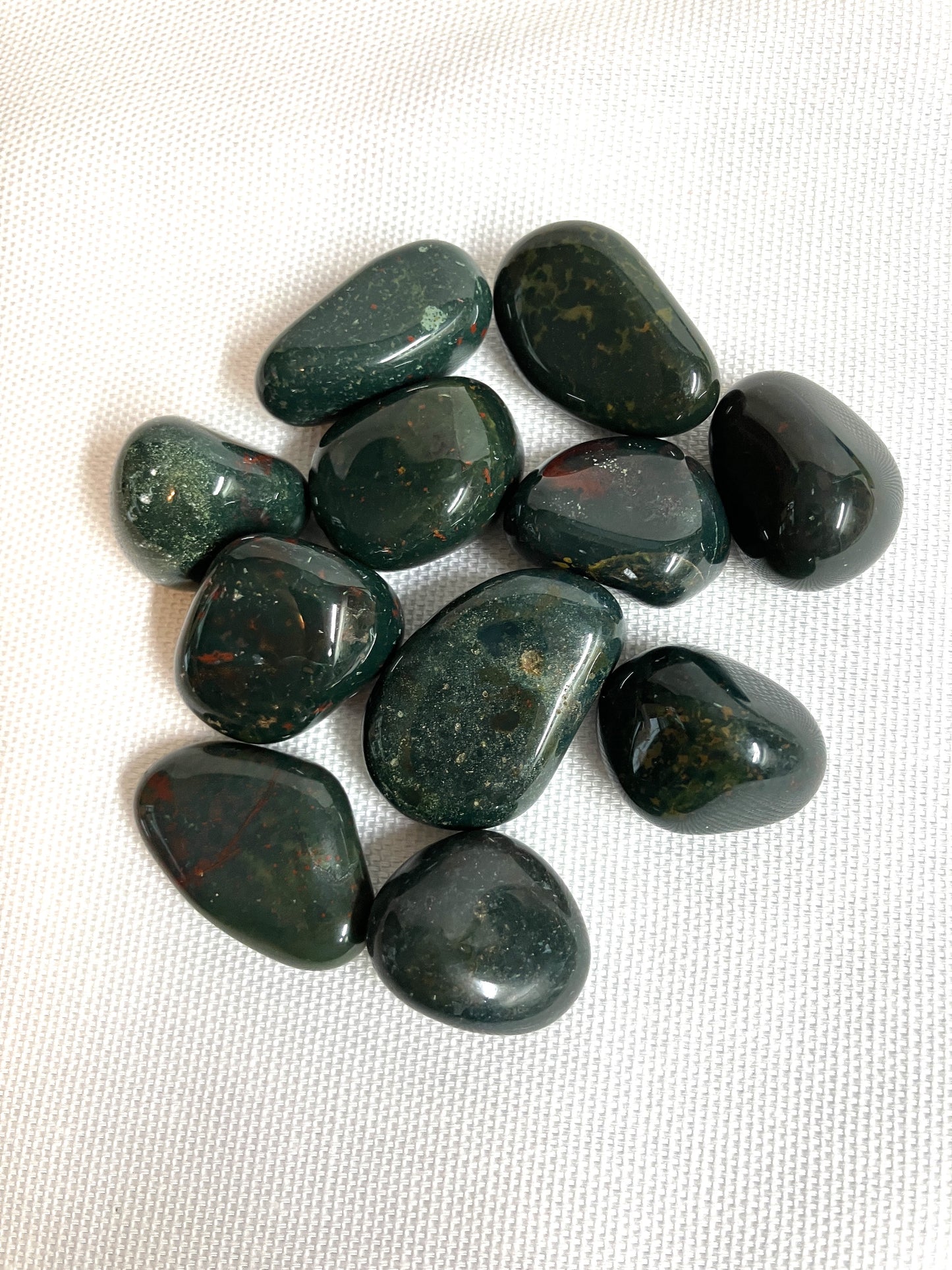 Group of Bloodstone Crystals showing the various differences between the crystals on a white fabric background