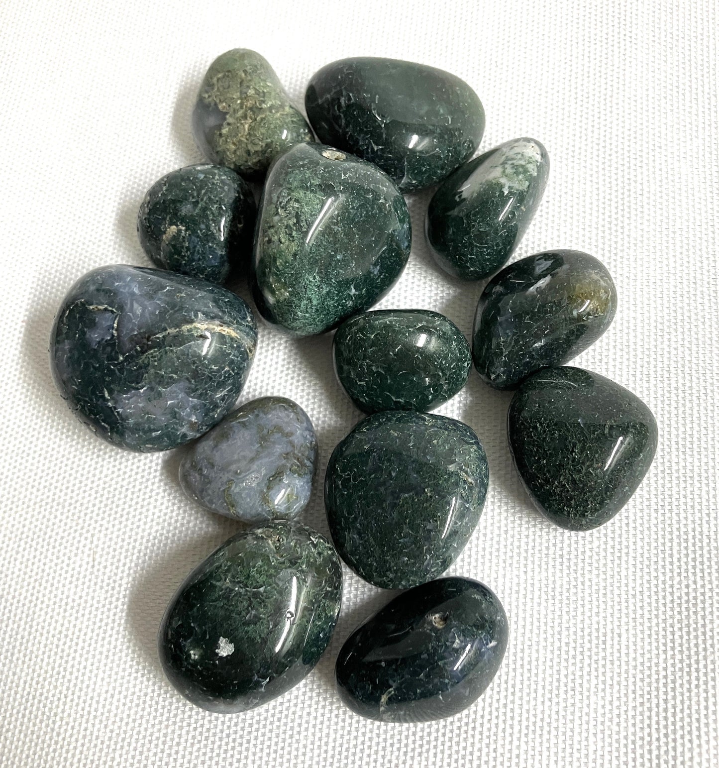 Moss Agate Crystals on a white fabric background
