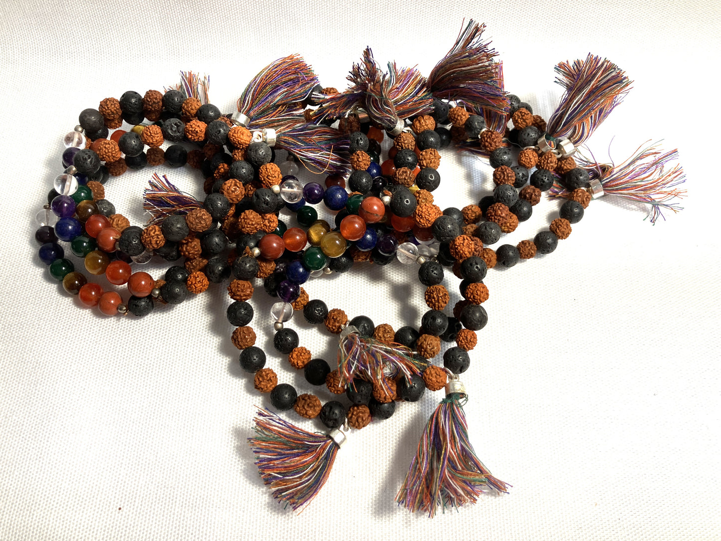 Chakra Stone Stretch Bracelet w/ Lava and Rudraksha Seeds with tassels on a white background