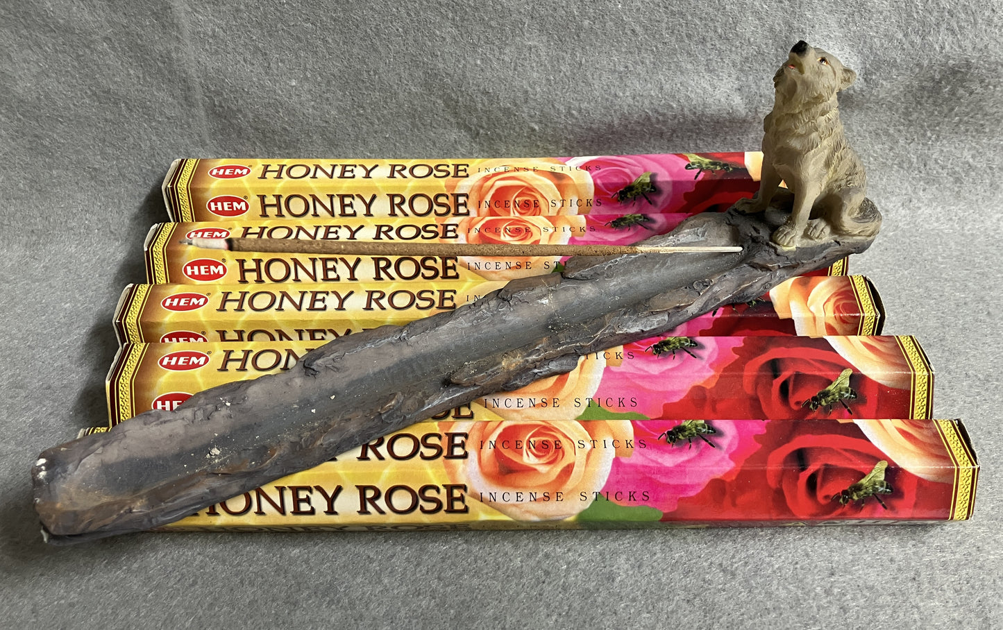 Honey Rose incense sticks with a Wolf figurine incense burner on a gray background