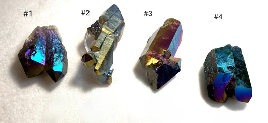 Four Titanium Plated Quartz crystal specimens with different color patterns on a light background