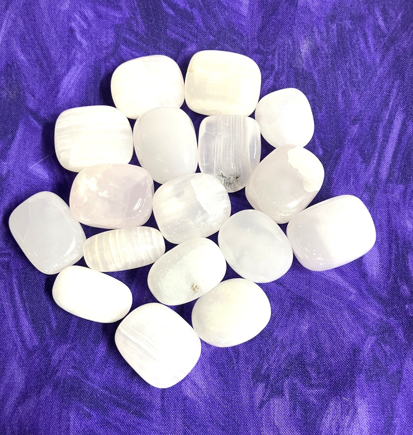 Natural light Pink Calcite Crystals on a purple textured fabric background