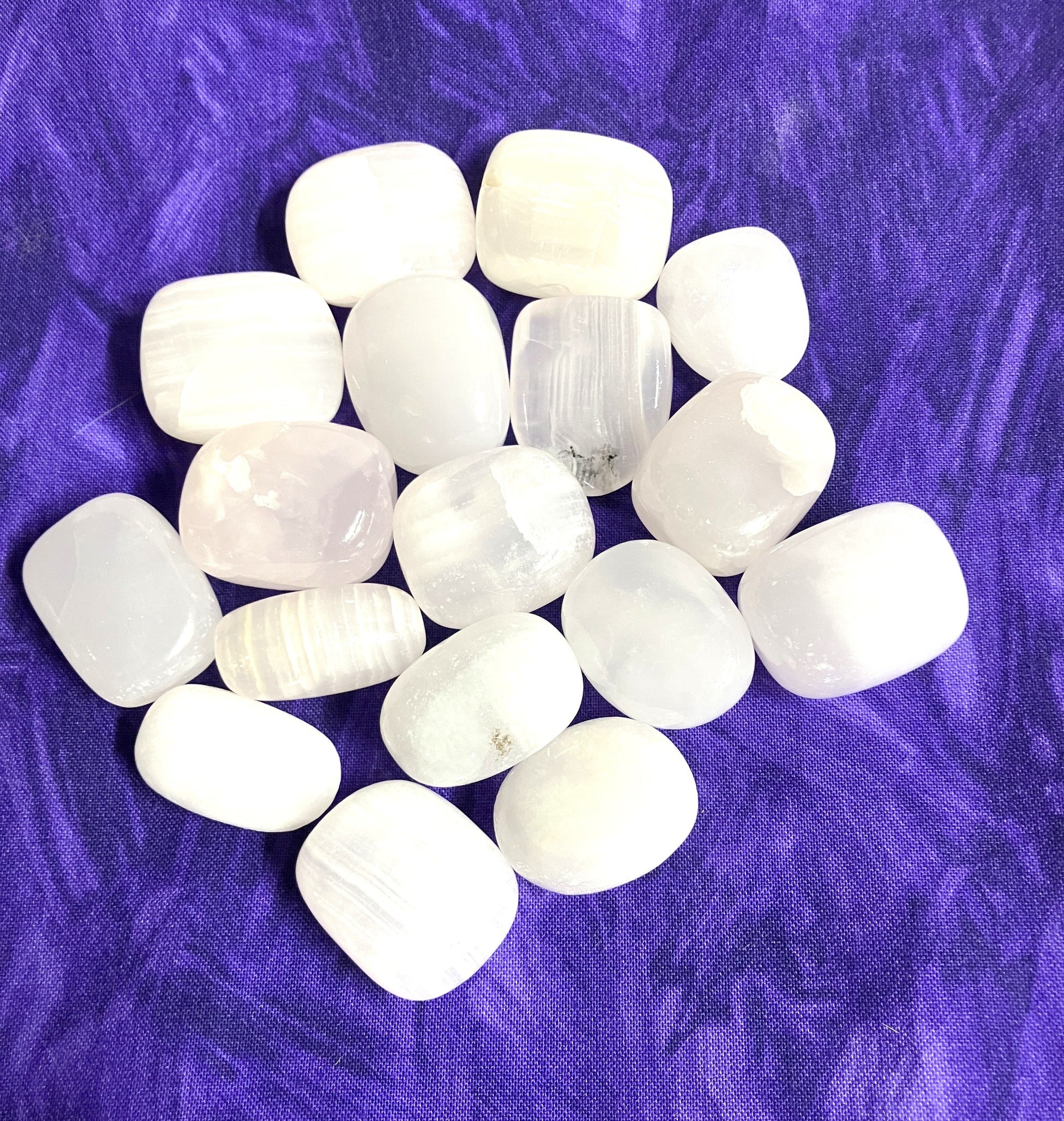 Natural light Pink Calcite Crystals on a purple textured fabric background