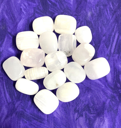 Natural light Pink Calcite Crystals on a purple textured fabric background