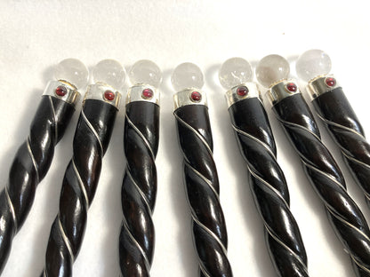 Closeup of a group of rosewood twisted wands showing the quartz orb, red accent and silver accents shown on a white background