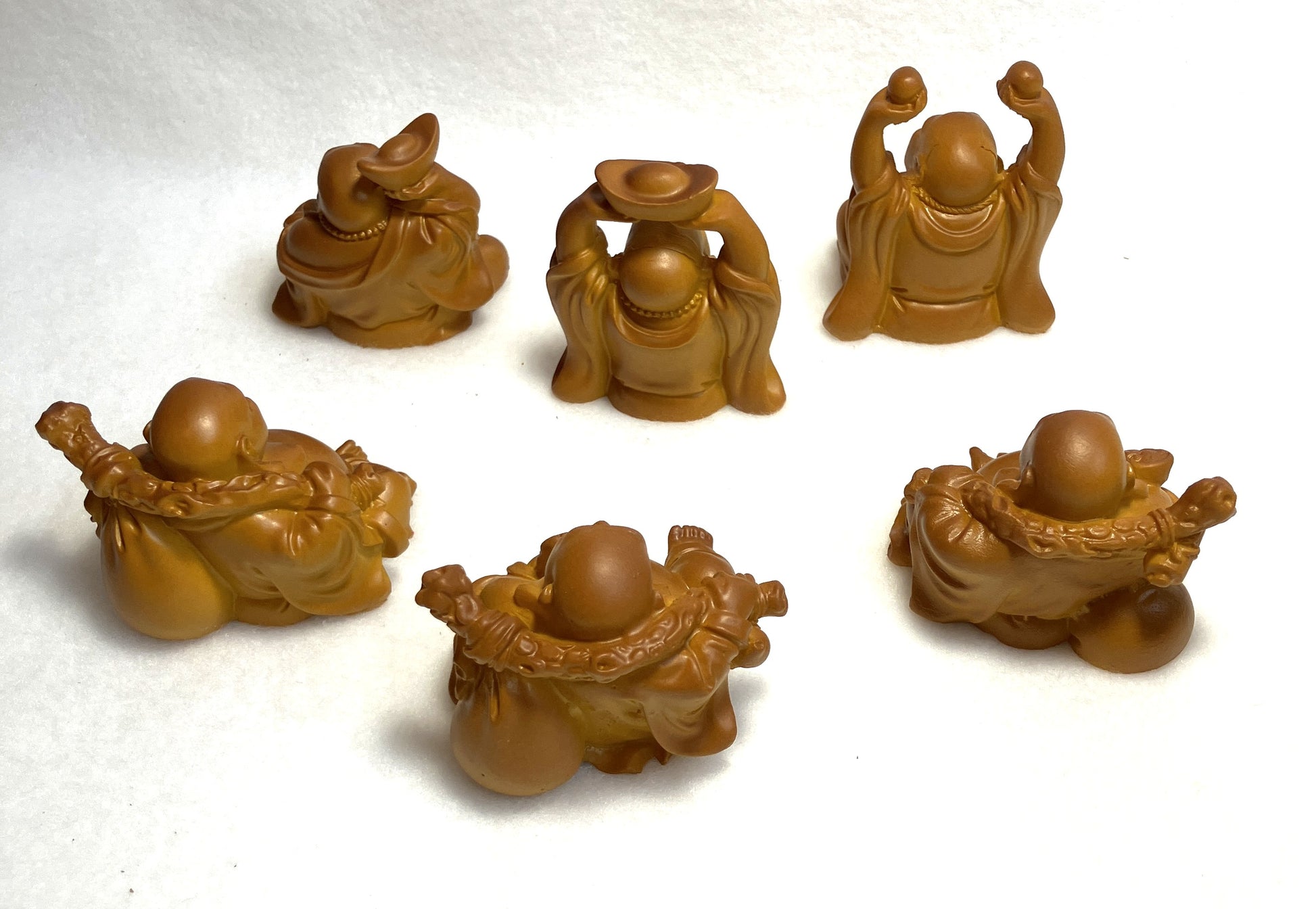 Set of six Laughing Buddha figurines showing their backs displayed on a white background