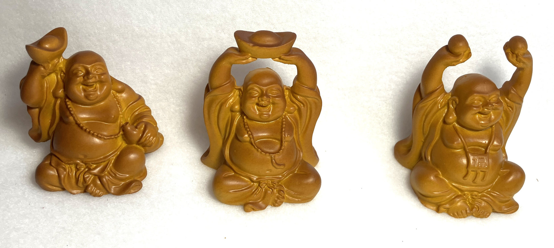 Closeup of Three Laughing Buddha figurines shown on a white background