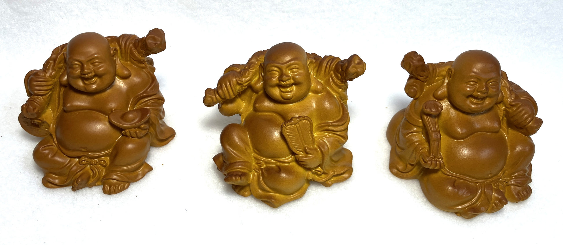 Three Laughing Buddha figurines shown close up on a white background