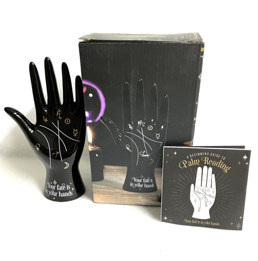 Black palm reading ceramic hand with a box and guidebook on a white background