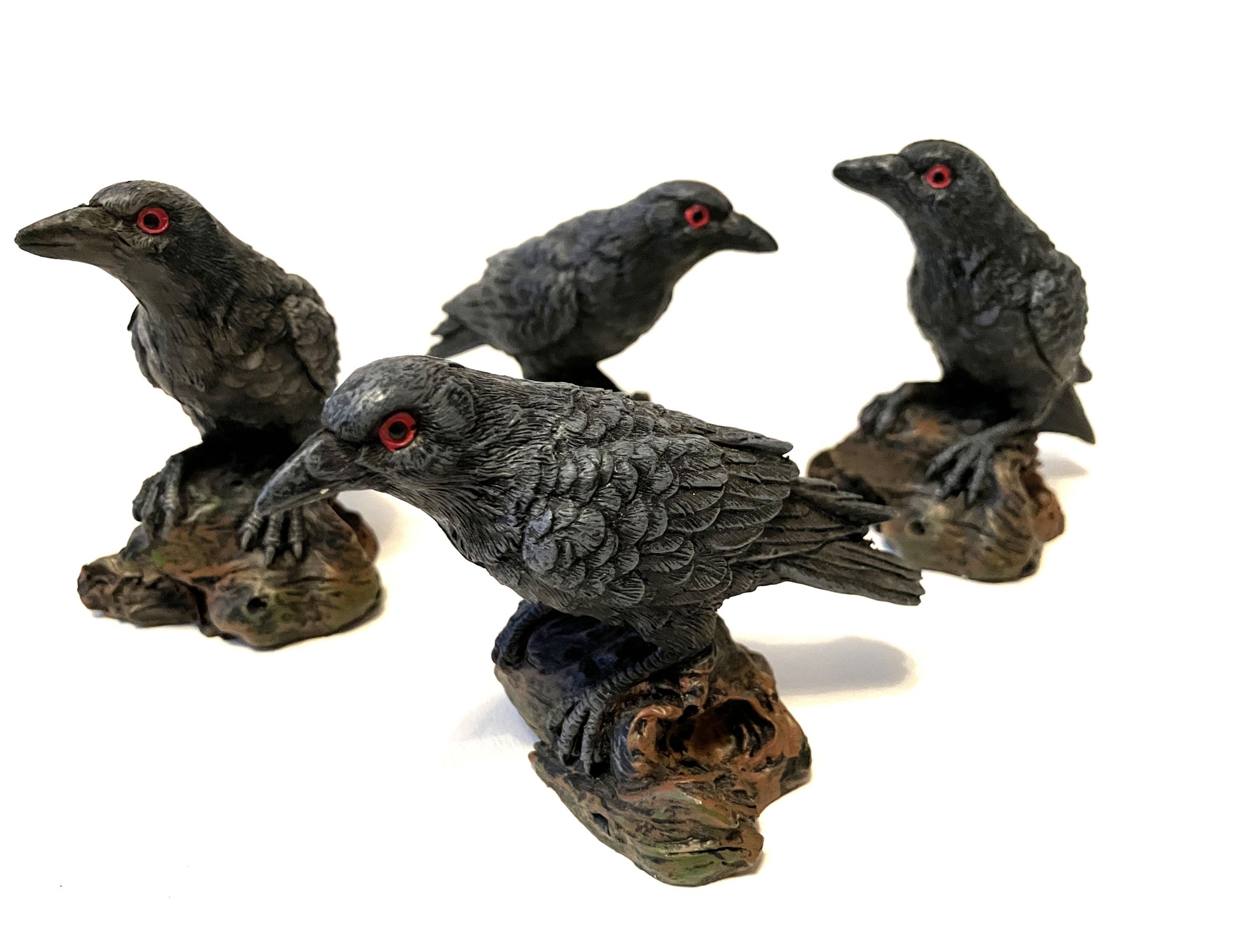 Four black bird figurines with red eyes on a white background