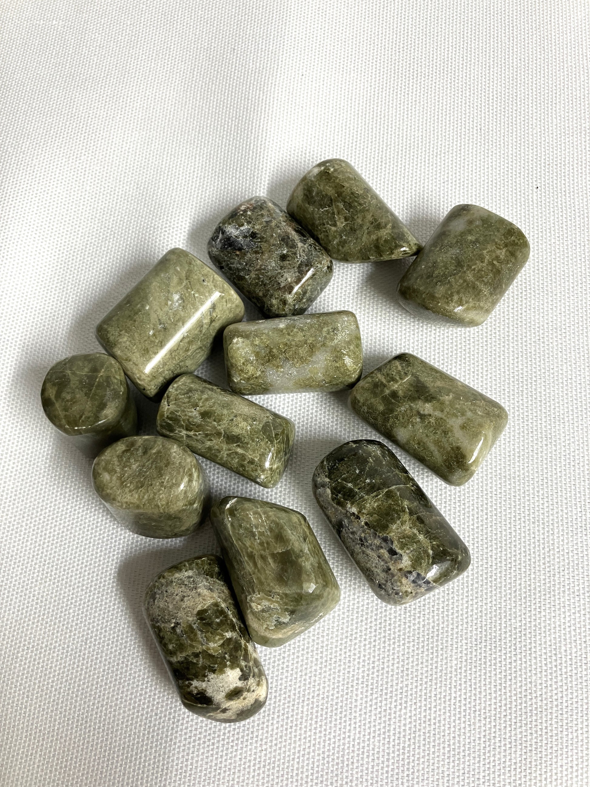 Front view of Vesuvianite Tumbled Crystals on a white fabric background
