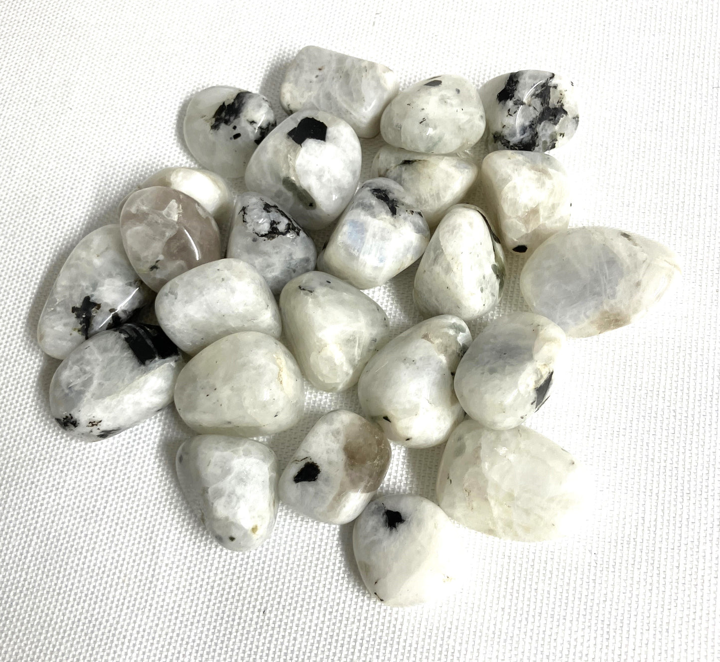 Tumbled Rainbow Moonstone Crystals  on a white fabric background