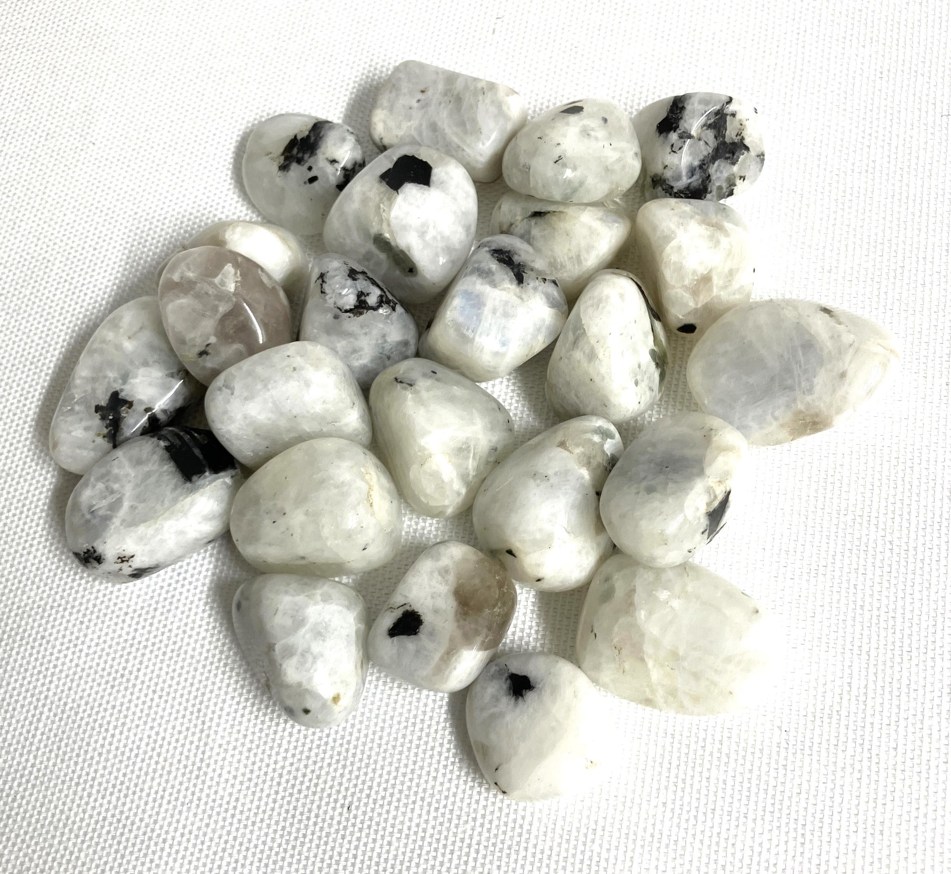 Tumbled Rainbow Moonstone Crystals  on a white fabric background