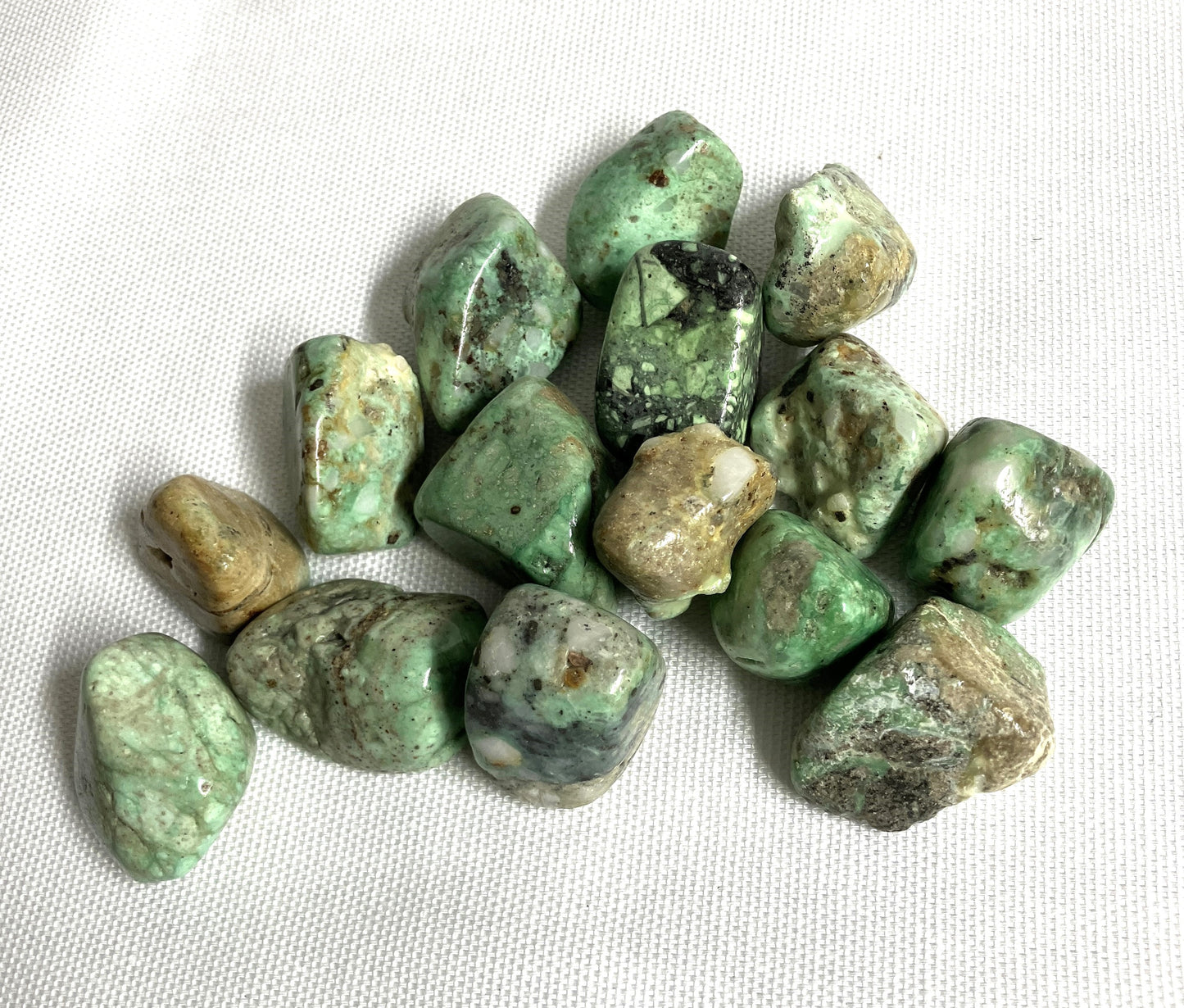 View of Variscite Crystals showing the variation of color and patterns on a white fabric background