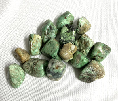 View of Variscite Crystals showing the variation of color and patterns on a white fabric background