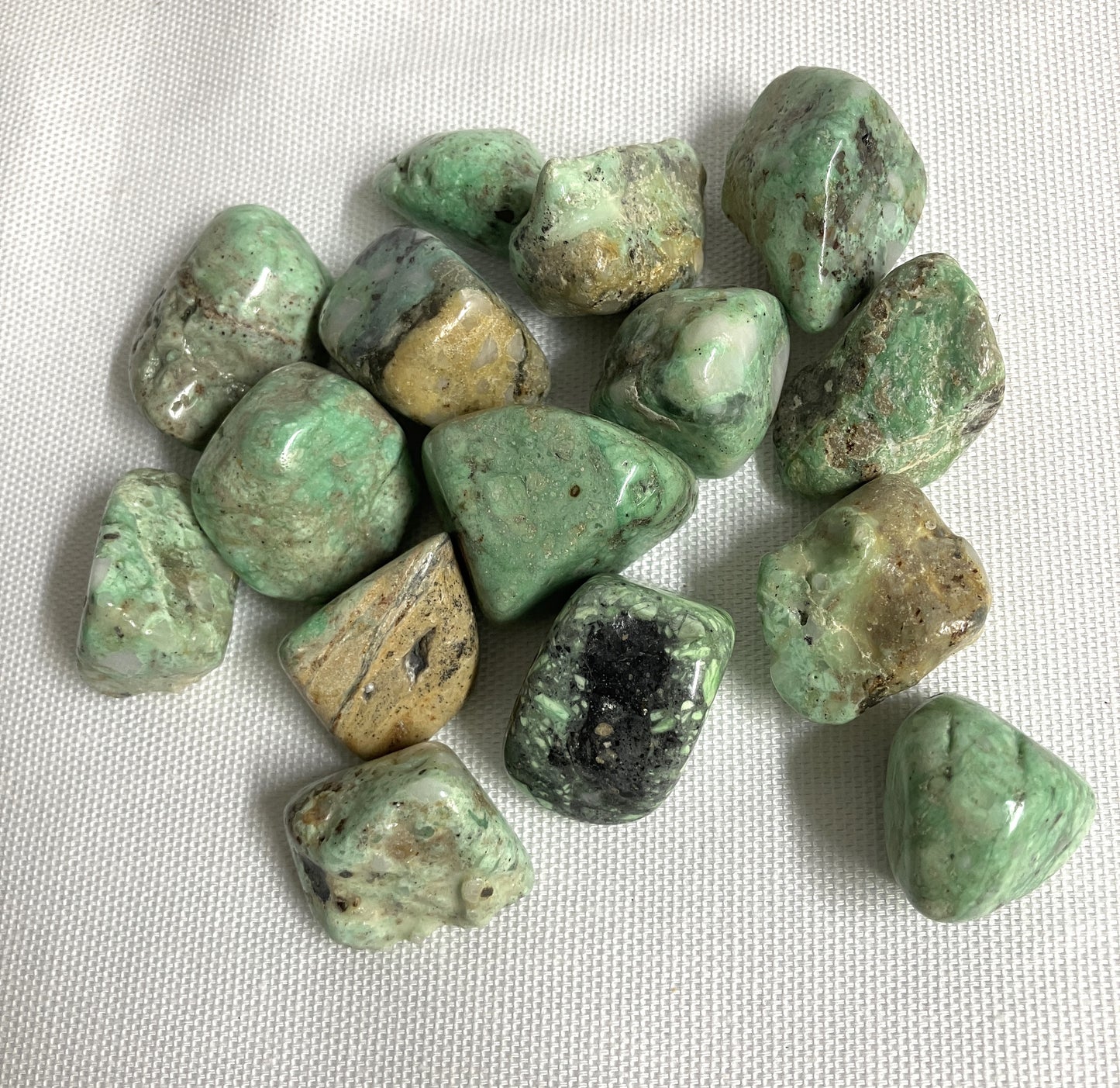 Collection of Variscite Crystals on a white fabric background front view