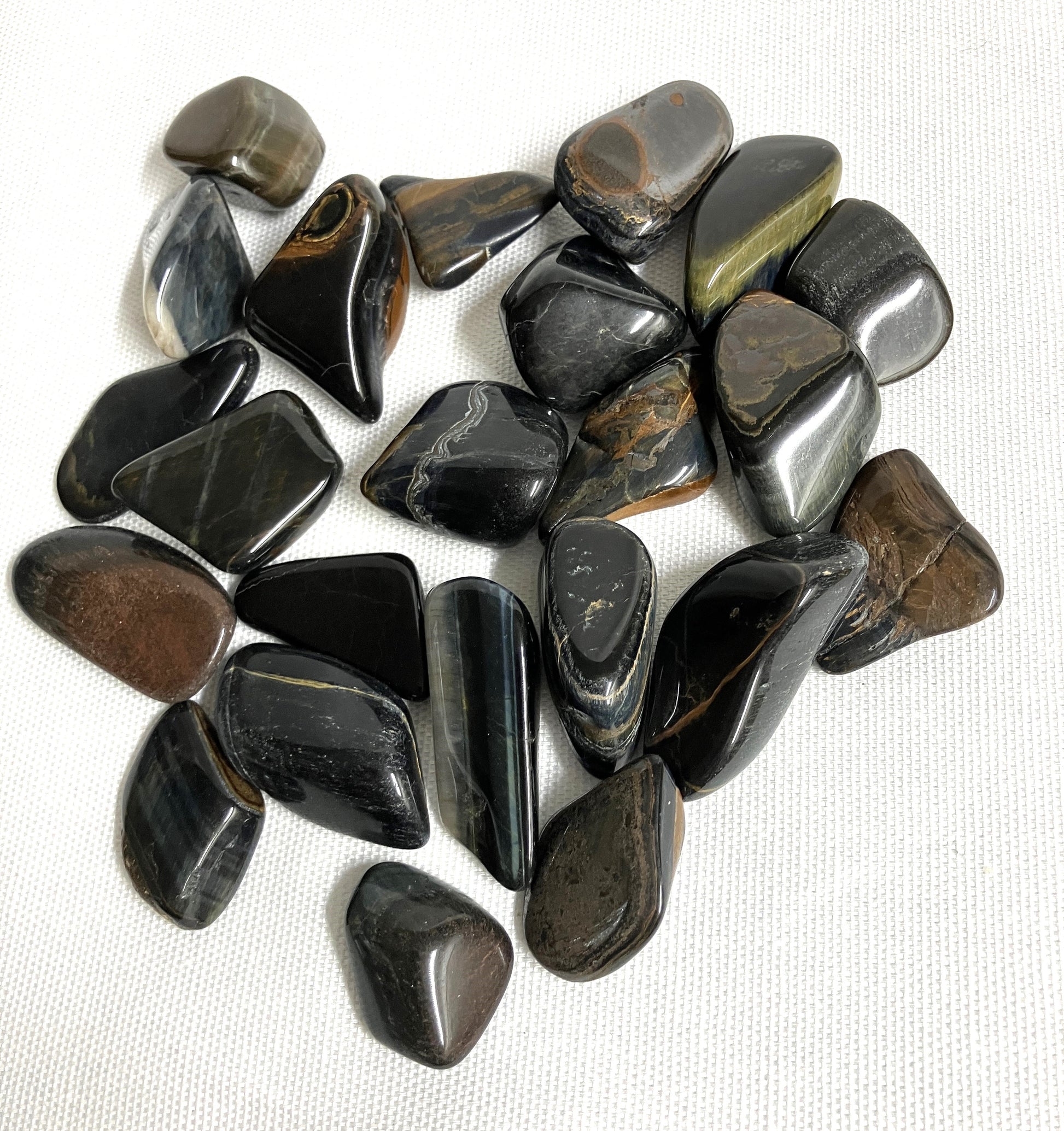 Group of Blue Tiger Eye Crystal AKA Hawks Eye AKA Falcons Eye showing size and variation of color on a white background