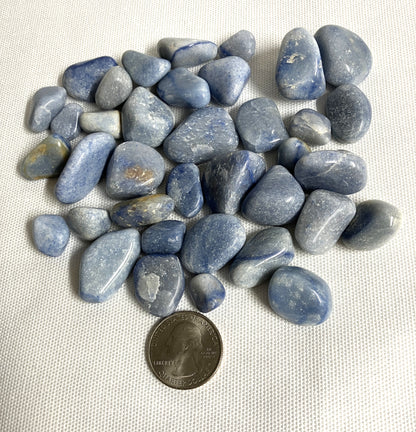 Back view of Blue Quartz Crystals on a white fabric background with a quarter for scale