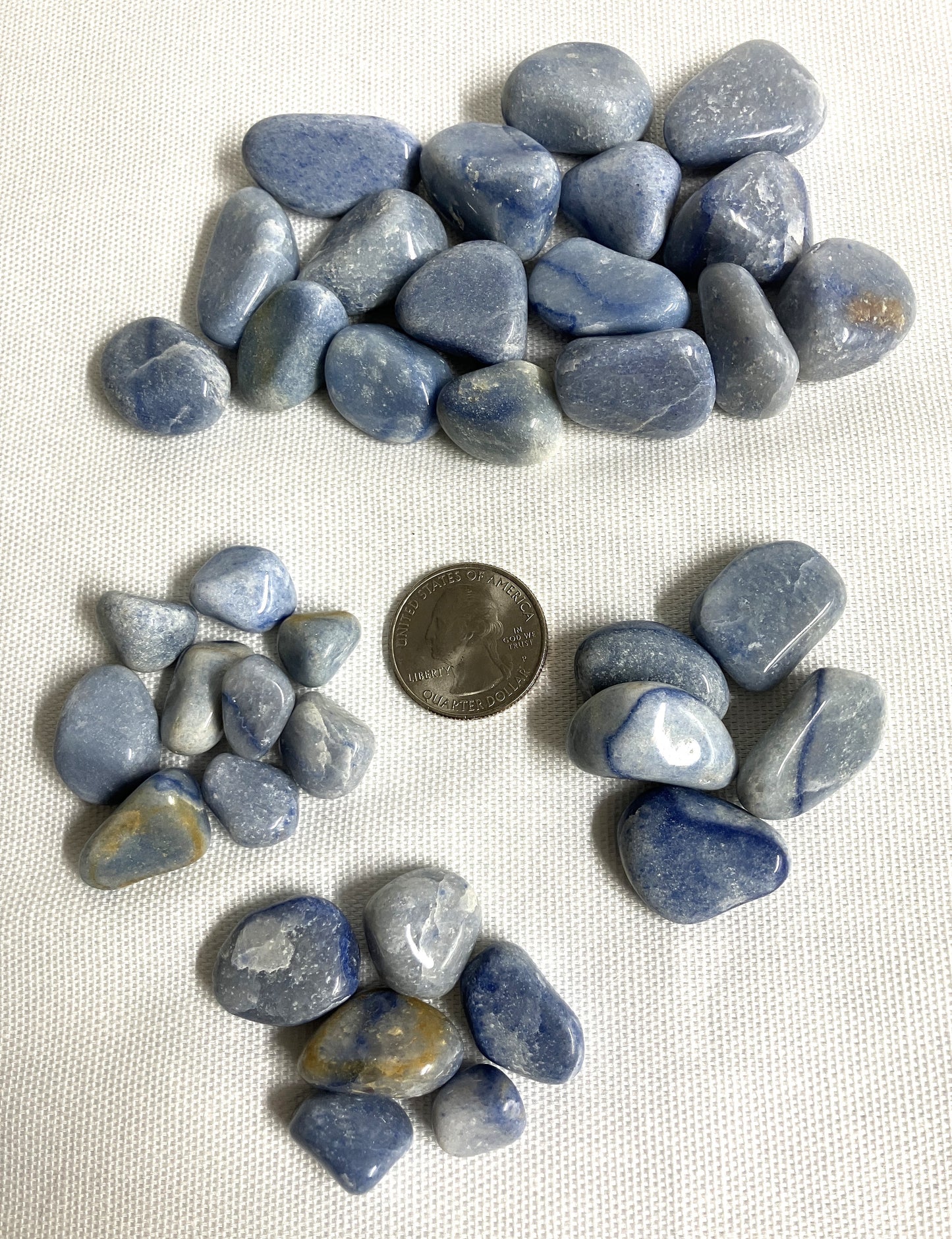 Group of Blue Quartz Crystals on a white fabric background with a quarter for scale