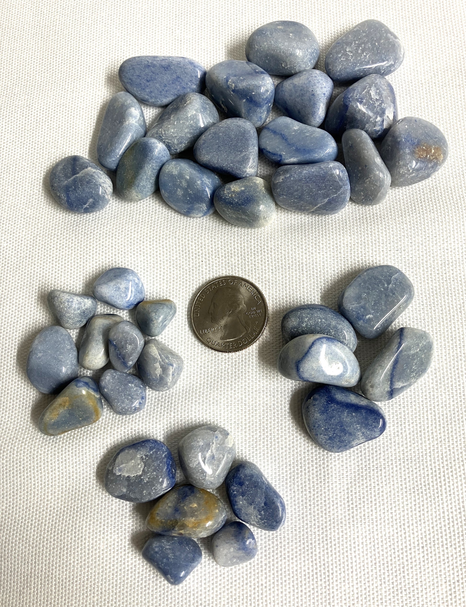 Group of Blue Quartz Crystals on a white fabric background with a quarter for scale
