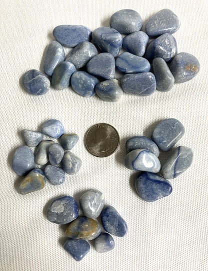 Group of Blue Quartz Crystals on a white fabric background with a quarter for scale