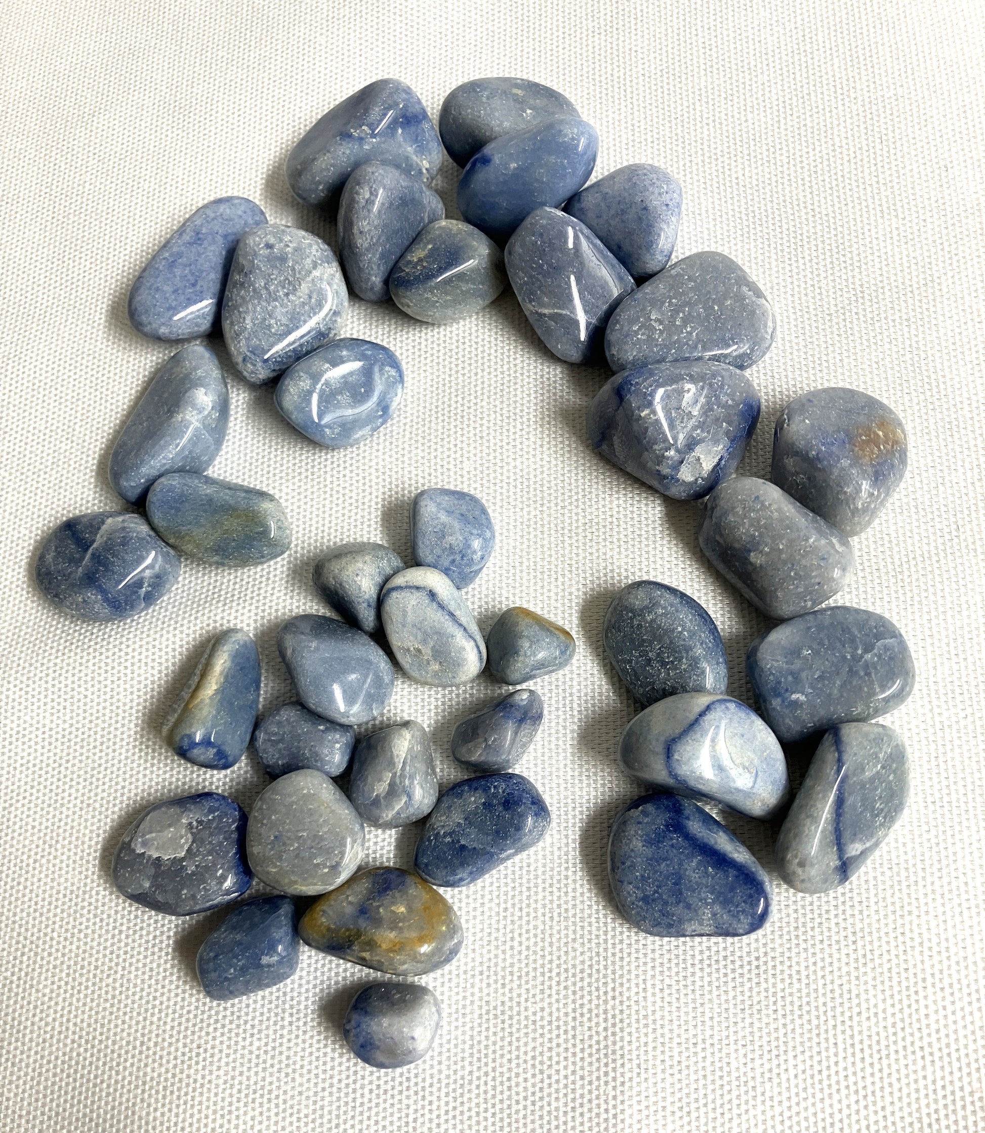 Collection of Blue Quartz Crystals front view arranged in a circular pattern on a white fabric background