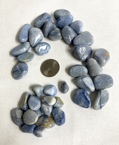 Blue Quartz Crystals arranged in a circular pattern with a Quarter for scale on a white background