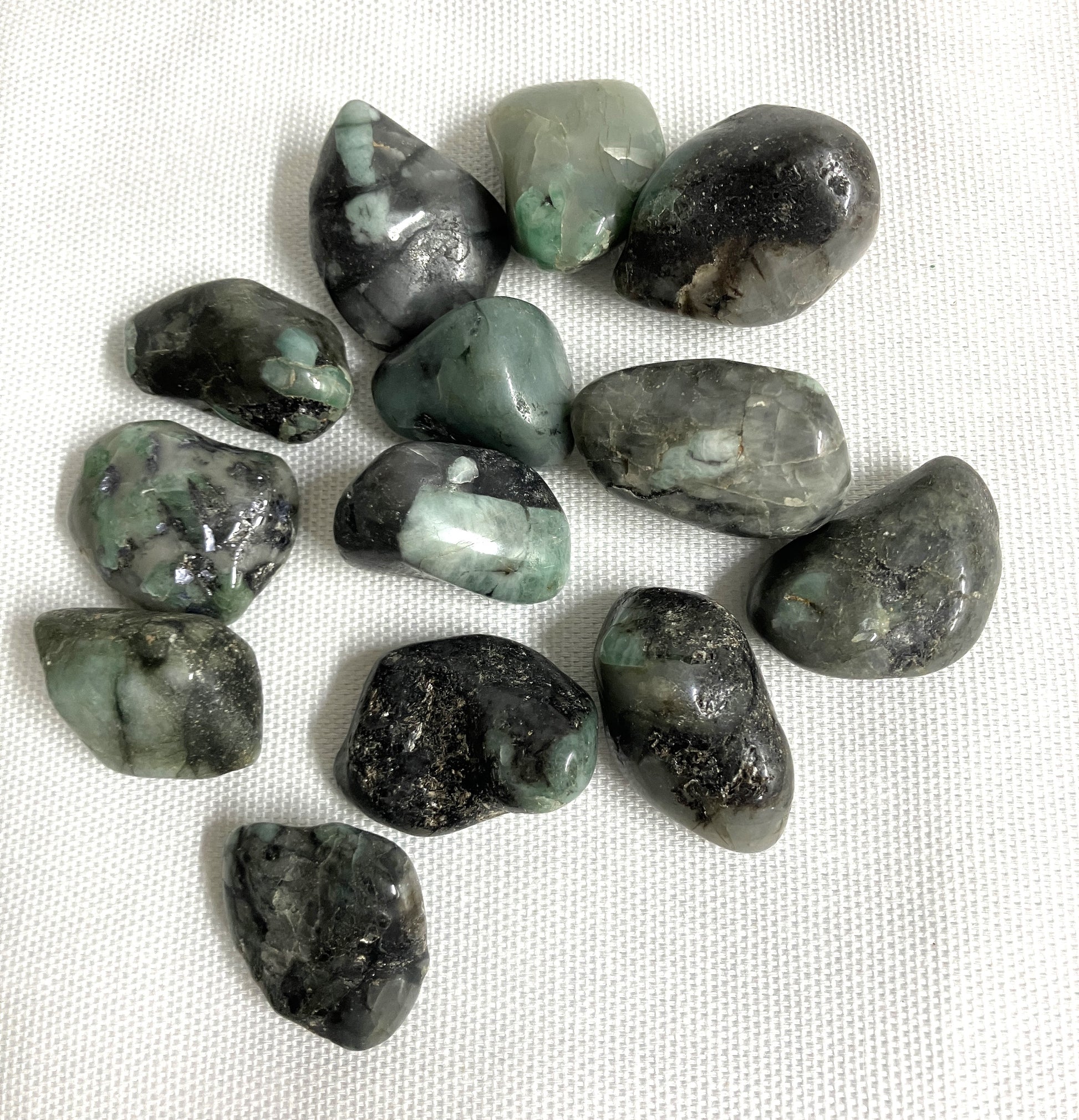 Collection of Emerald Crystals on a white fabric background front view