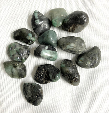 Collection of Emerald Crystals on a white fabric background front view