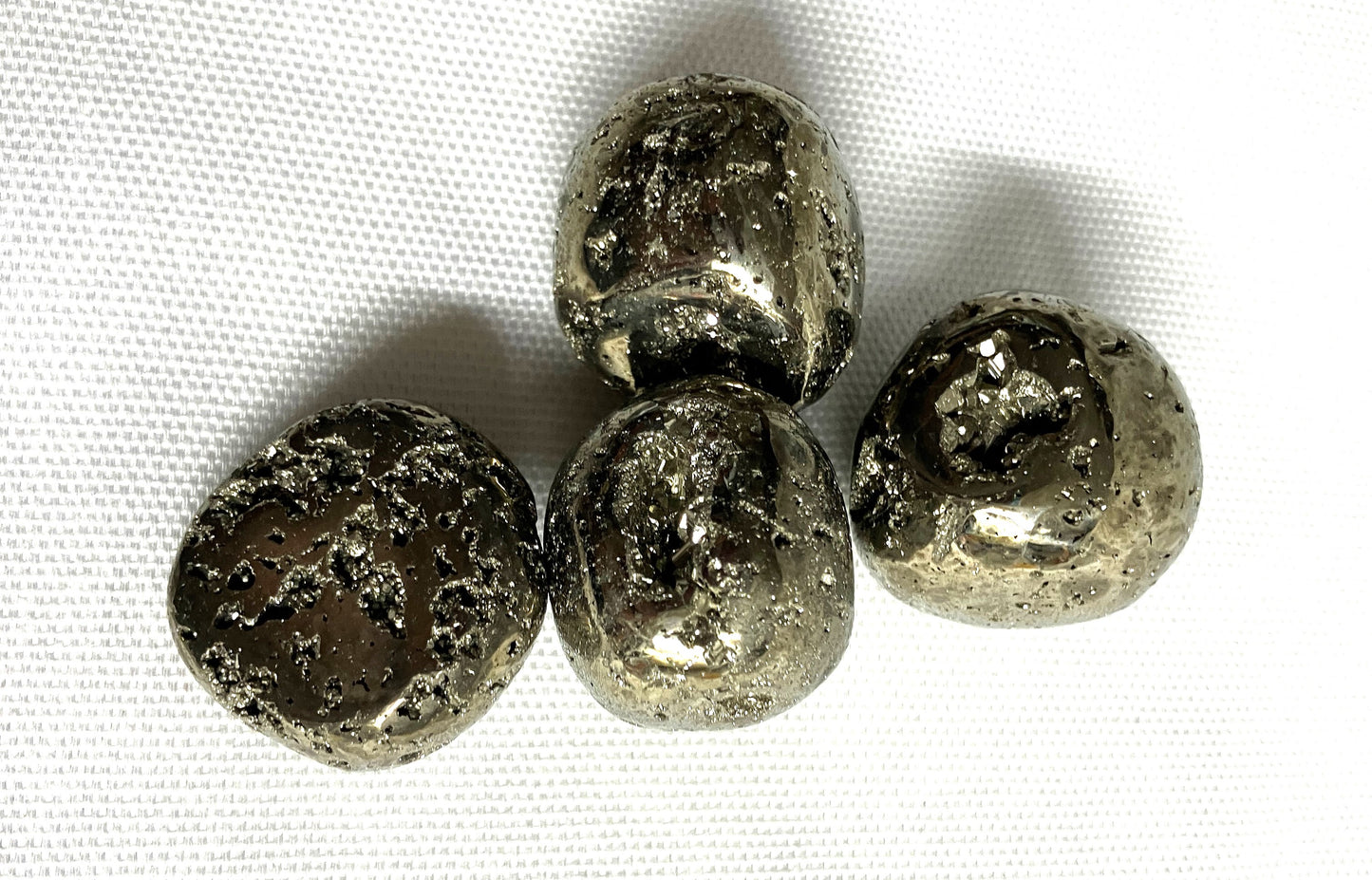 Closeup of Tumbled Pyrite Crystal AKA Fool's Gold  on a white fabric background