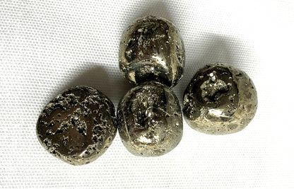 Closeup of Tumbled Pyrite Crystal AKA Fool's Gold  on a white fabric background