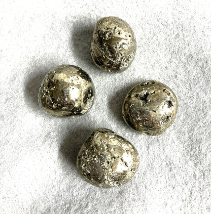 Tumbled Pyrite Crystal AKA Fool's Gold  shown on a textured white surface