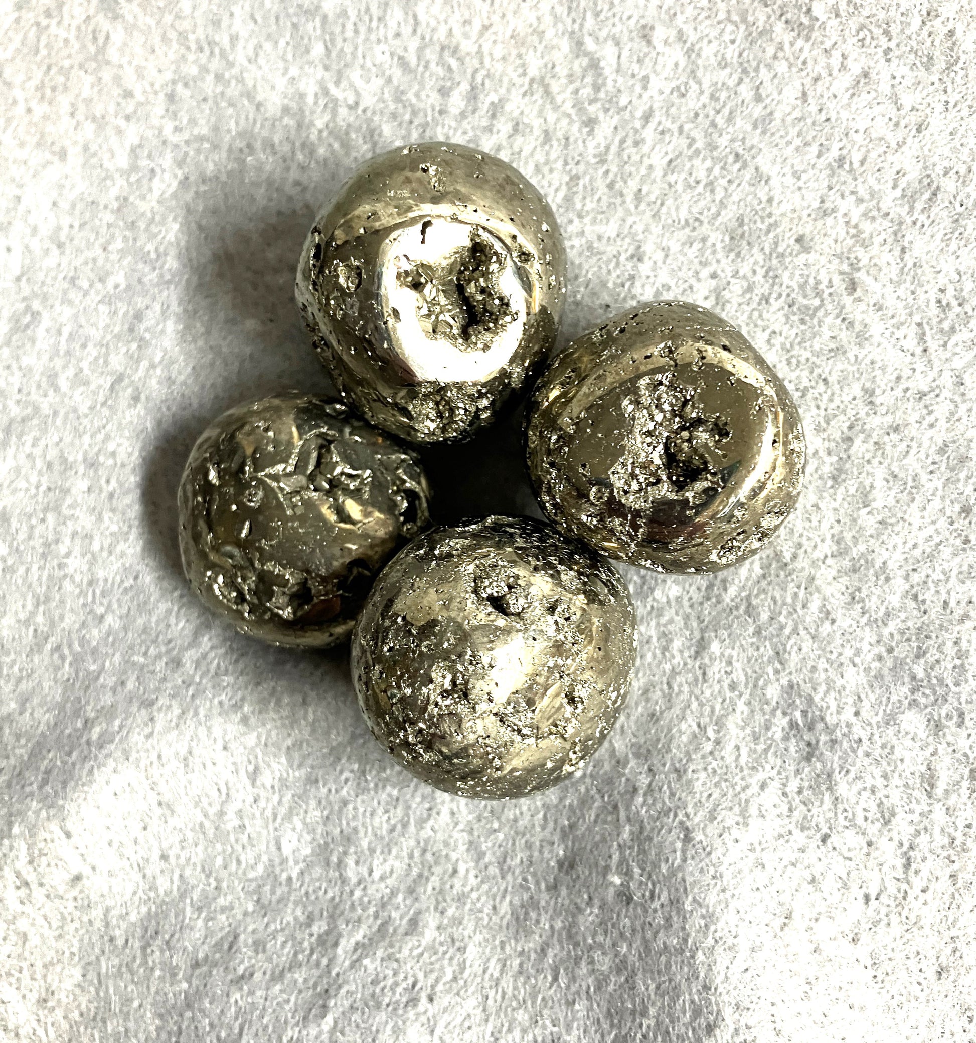 Selection of Tumbled Pyrite Crystal AKA Fool's Gold  on a textured gray surface